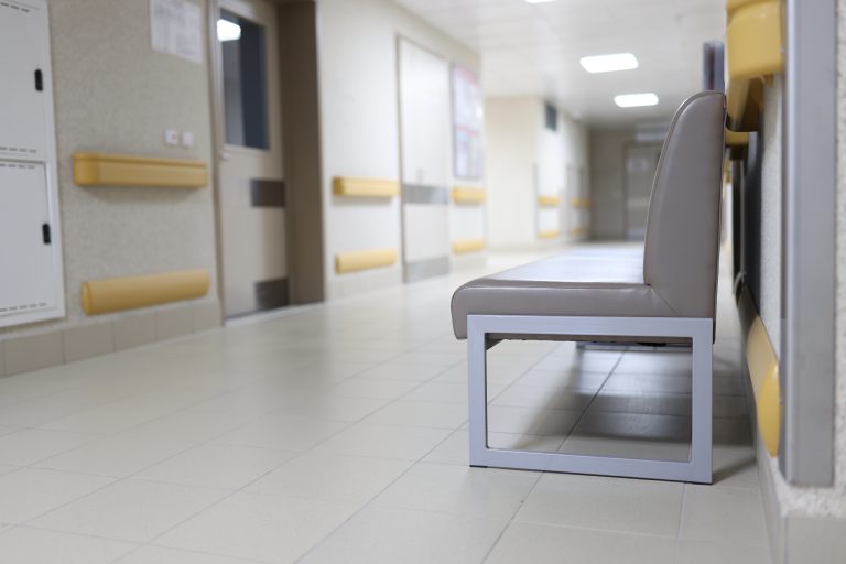 Gray couch standing in empty hospital hallway. Clinic work concept
