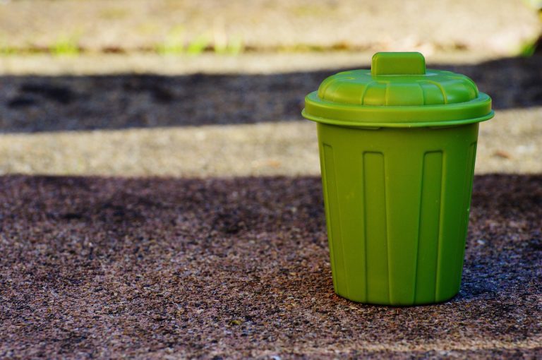 small green bin on concrete floor outside